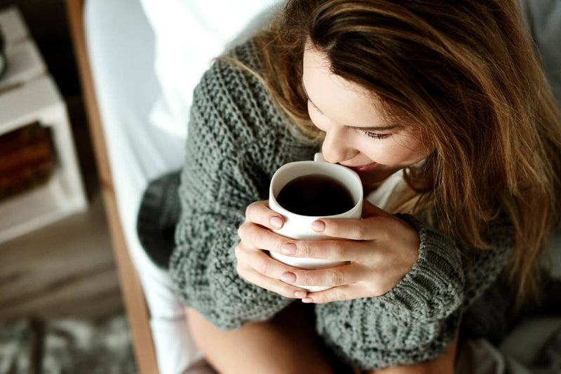 Mulher tomando café sentada na cama